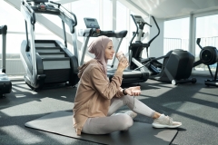 Young serene sportswoman drinking water after training